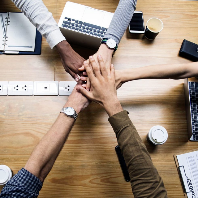 hands stacked in huddle over center of table