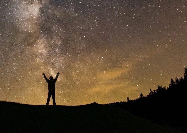 person standing triumphantly against a backdrop of stars